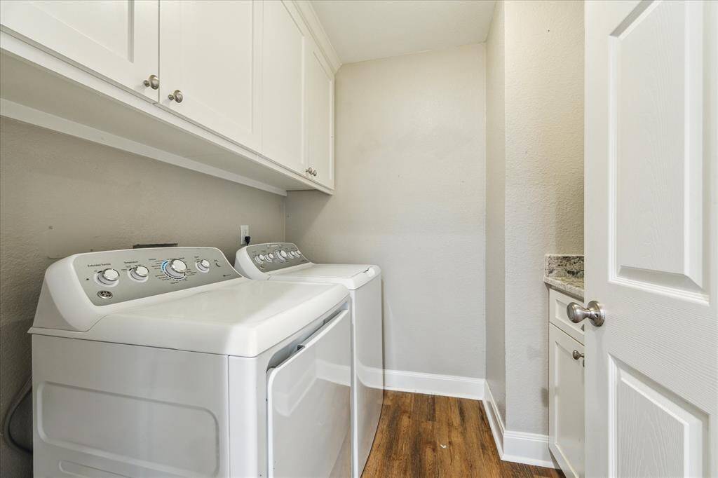 The spacious utility room includes upper cabinets, granite-topped folding space, and a full-size washer and dryer set.