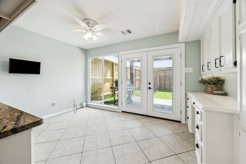 The kitchen opens effortlessly to the breakfast area, with double glass French doors leading to the back patio. Also features a built-in nook for added storage or display.
