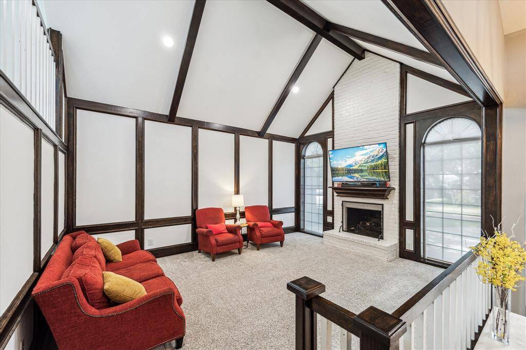 The cozy living room features a floor-to-ceiling brick fireplace upgraded with a new gas log insert accented with colored glass and remote control. Enhancements include electrical wiring for a TV mount and a brand-new chimney cap.
