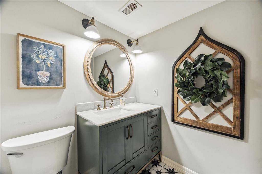 The half bathroom has been completely remodeled, featuring a custom vanity and matching mirror.