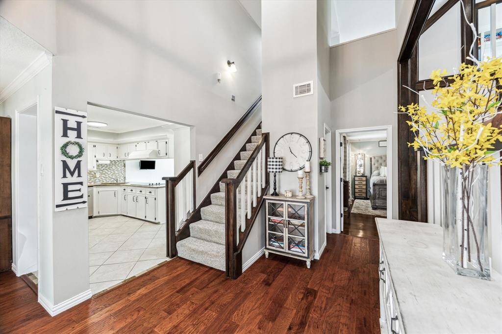 Step into a grand entrance with soaring two-story ceilings and newly installed engineered hardwood flooring that flows seamlessly through the entryway and formal dining room.