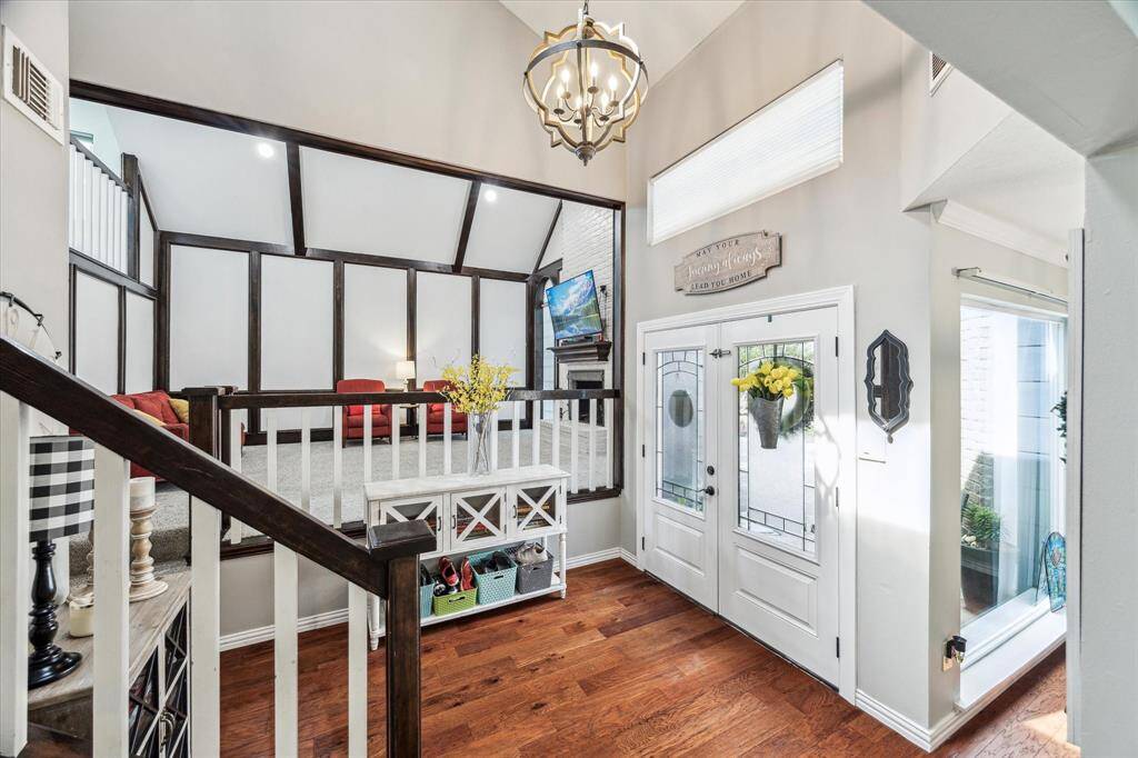 The double door entrance opens into a bright and inviting foyer, showcasing the raised family room with custom wood trim and vaulted ceilings.