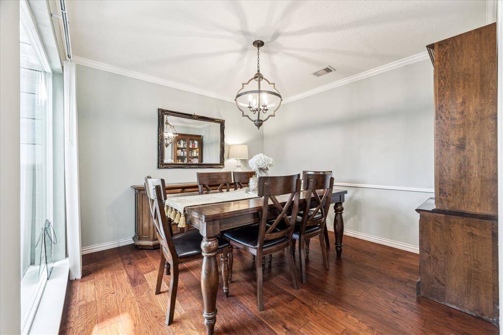 Enjoy formal gatherings in this beautifully updated dining room featuring new crown molding and baseboards throughout the home, and an elegant chandelier that perfectly complements the rich wood flooring.