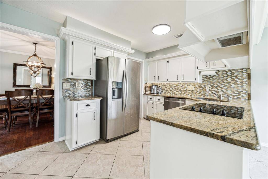 Kitchen featuring granite countertops and freshly painted cabinets with updated hardware. Conveniently located just steps from the dining area - making mealtime and gatherings a breeze.