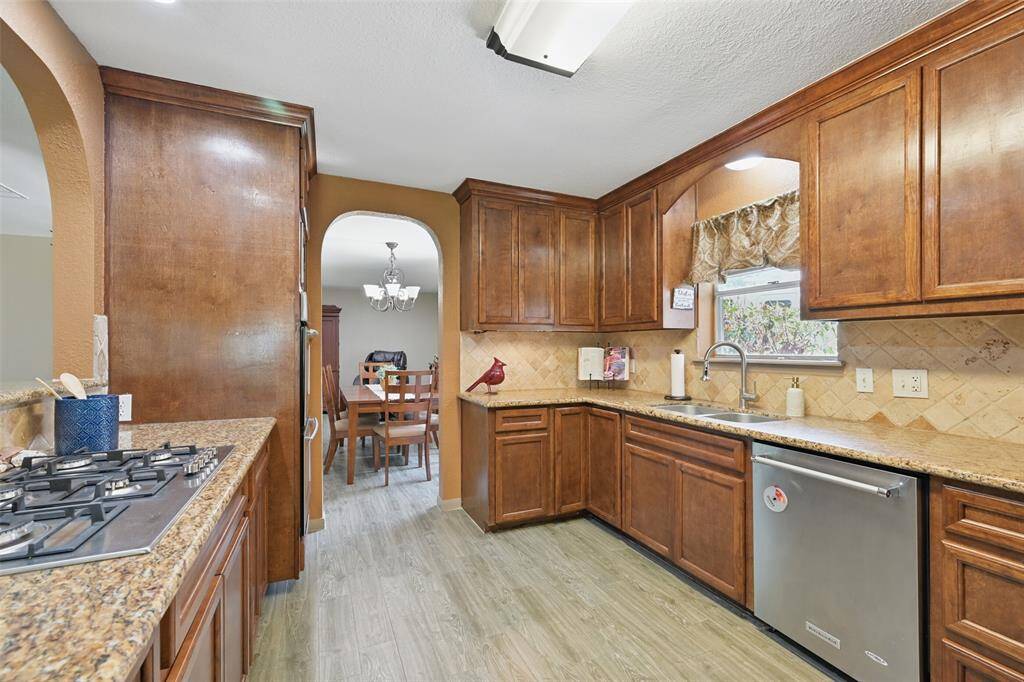 Kitchen with granite counters, gas cooktop, double oven, microwave with window that overlooks driveway. Laundry room is right off of the kitchen and features additional storage.
