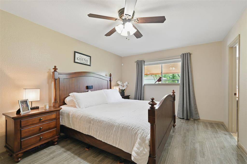 Primary bedroom overlooks the backyard, has a large walk-in closet, neutral paint, tile floors, updated ceiling fan.