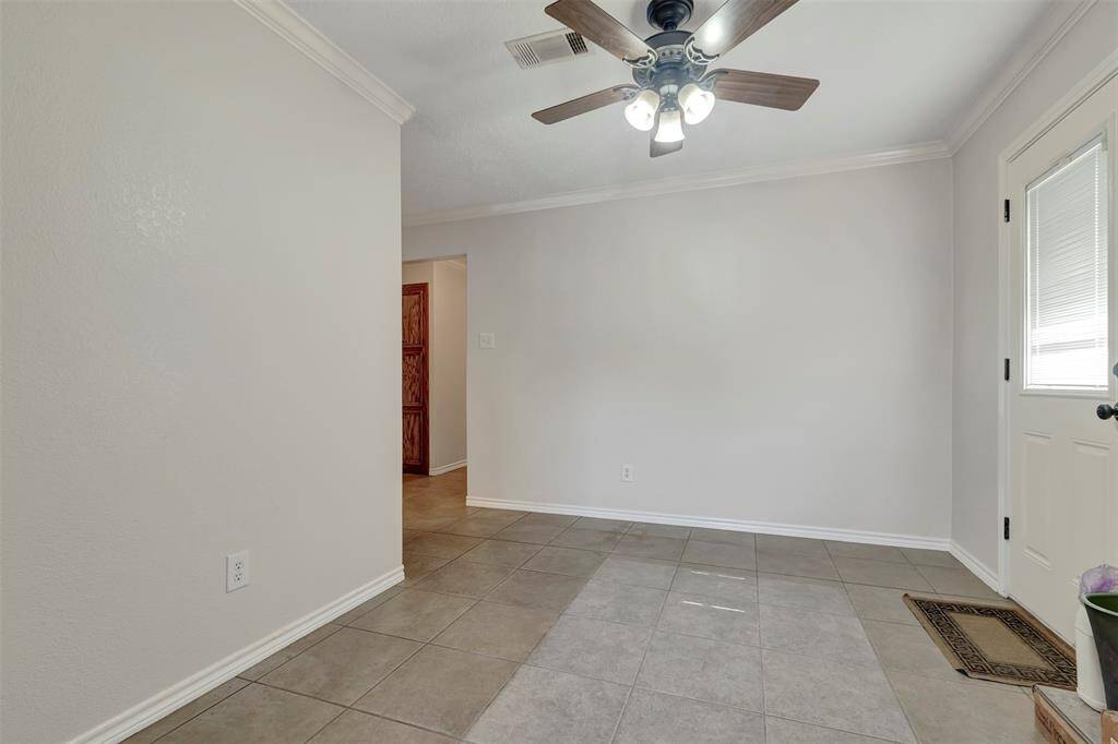 A closer look at the dining area, featuring a ceiling fan and a door that opens to the backyard.