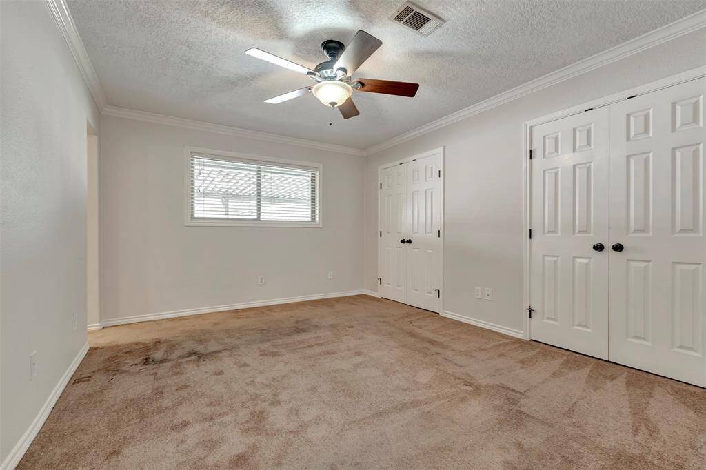 Welcome to the spacious primary bedroom with carpeted floors and great potential for the new owner. The closed doors lead to the wardrobe.