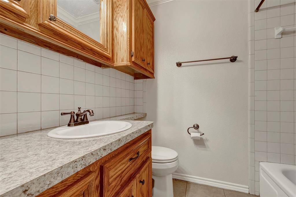 This primary bathroom features a tub and shower combo, along with cabinets for additional storage.