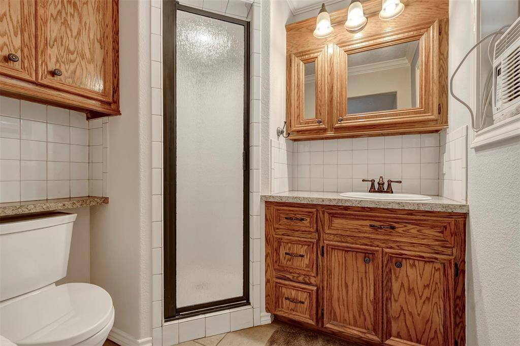 The shared secondary bathroom features a tiled backsplash, a standing shower, and wood-patterned cabinetry.