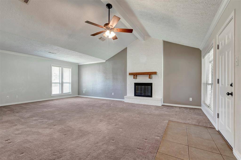 This inviting space features a carpeted floor and a classic wood-burning fireplace—perfect for cozy evenings at home.