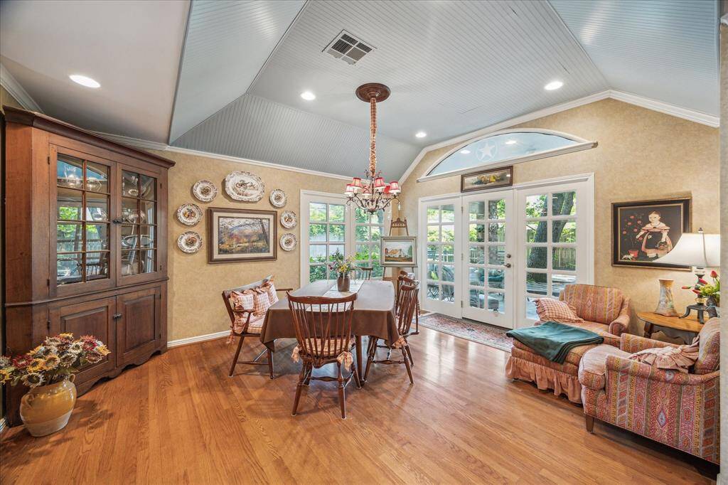 This large breakfast room just off the kitchen offers ample space for dining and a cozy sitting area, with walls of fixed French doors—one leading to the patio—filling the space with light. Featuring a charming tray tongue-and-groove ceiling, it flows effortlessly into the family room, creating the perfect setting for gathering and making lasting memories.