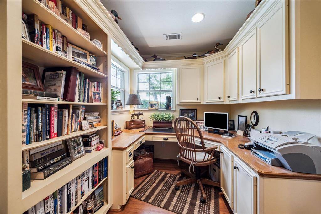 This home office features a wall of built-in bookshelves, amble cabinet storage, spacious wrap around desk and even built-in file drawers (not shown).  Strategically positioned over looking the pool creates an open ambiance while maintaining a sense of separation.