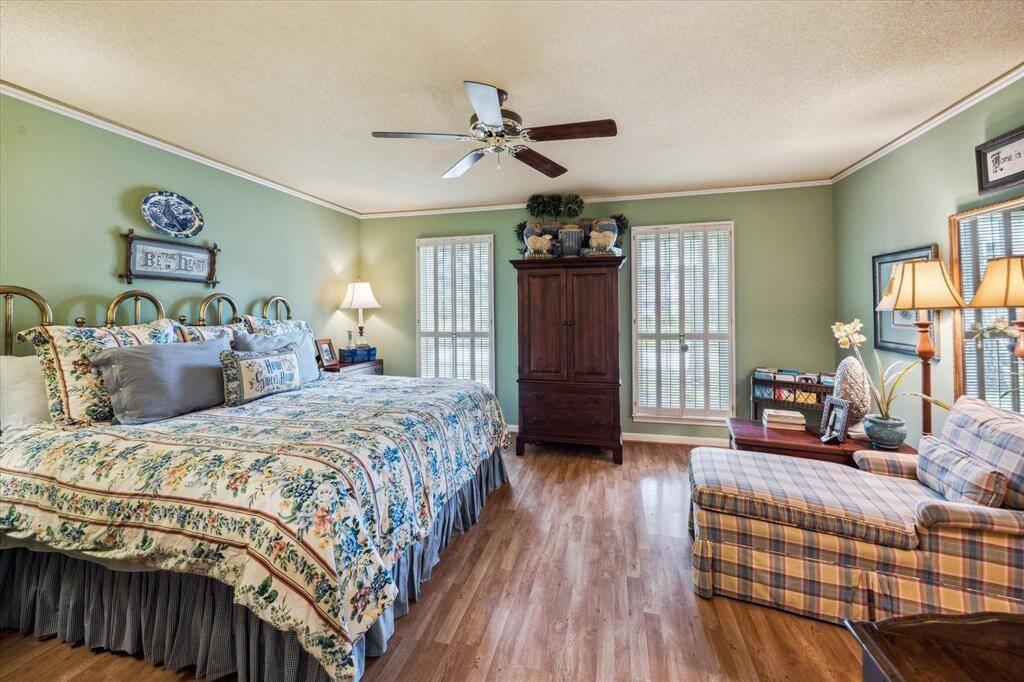 The primary bedroom is a serene retreat featuring rich wood floors that add warmth and elegance. The spacious sitting area offers the perfect spot to relax, unwind, or enjoy a quiet moment with a book.