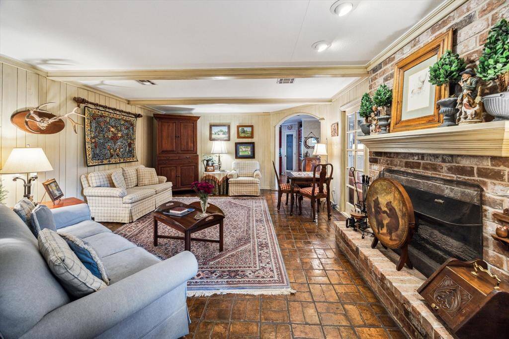 The family room is a warm and character-filled gathering space. Antiqued paneled walls lend an air of old-world charm and artistry, creating a one-of-a-kind ambiance that sets the tone for the entire home.  At the heart of the space is a large brick gaslog fireplace—perfect for cozy evenings and creating a focal point that anchors the room with both function and beauty.