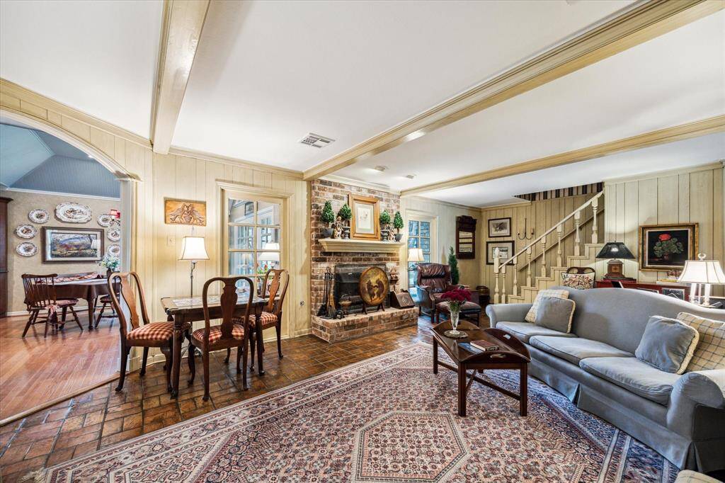 The stained brick flooring complements the fireplace and ties the room together with earthy richness and texture, offering both durability and visual warmth. A large arched opening gracefully connects the family room to the adjoining kitchen and breakfast area, allowing for seamless flow and easy entertaining. This thoughtful layout blends openness with defined spaces, ideal for both relaxed family living and hosting guests.