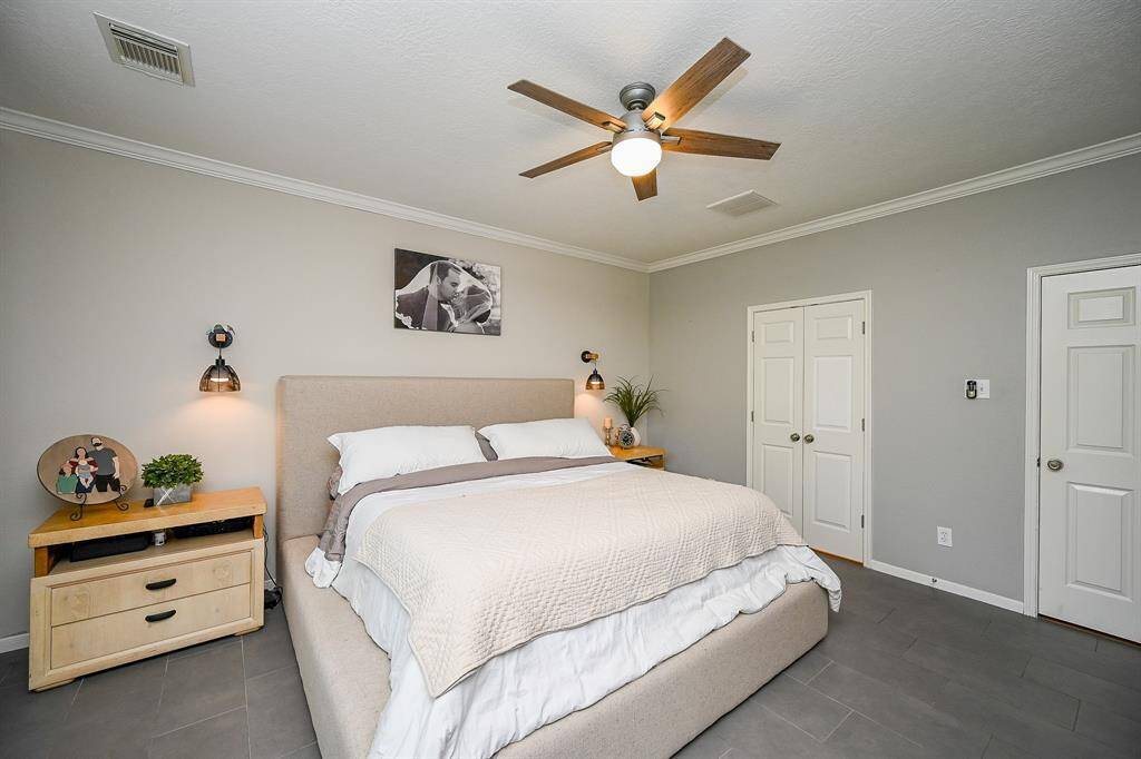 This bedroom features a cozy, modern design with a neutral color palette. It has a stylish ceiling fan, and ample natural light.