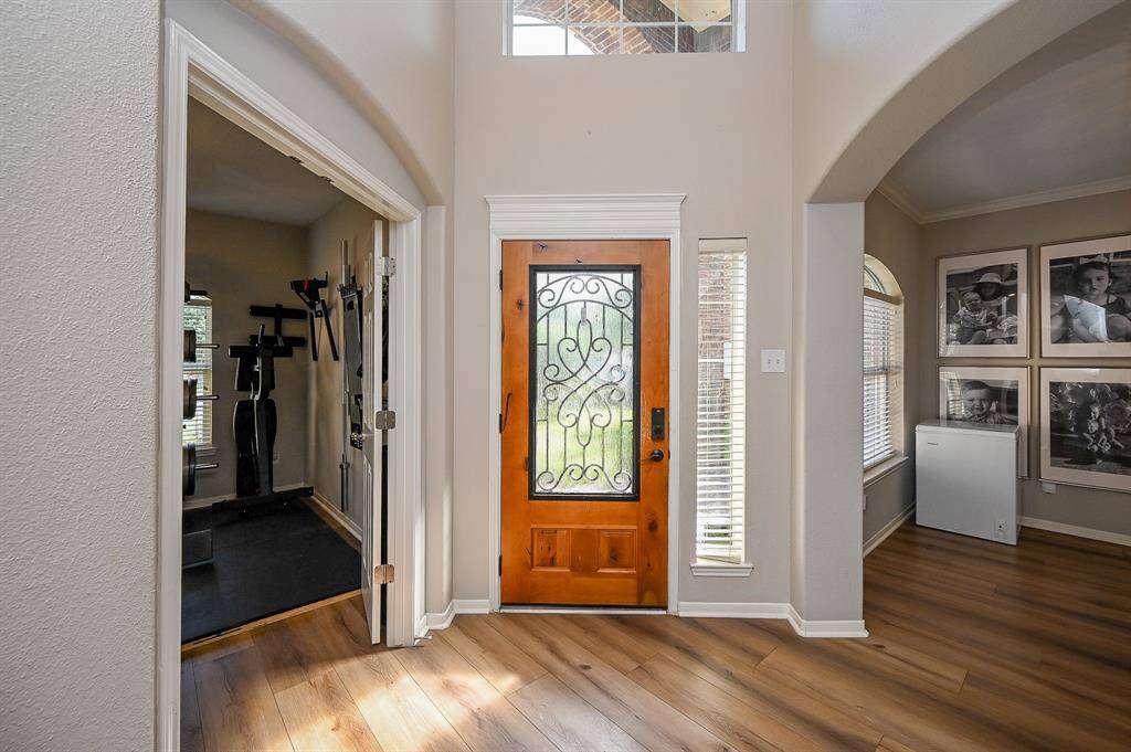 This welcoming entryway features a wooden door with decorative glass, leading into a bright space with 8" wide vinyl plank flooring. Adjacent is a Study/Flex Room, and there's a formal dining with windows.
