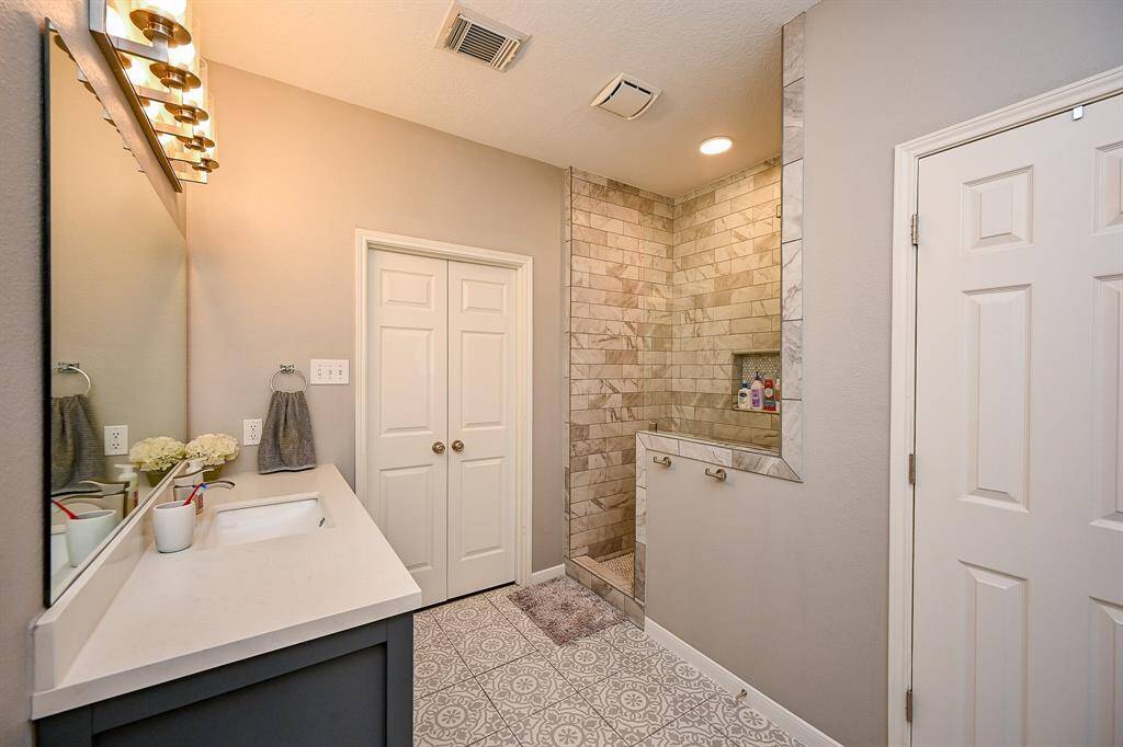 This bathroom features a modern design with a spacious walk-in shower, elegant tile work, and a large vanity with ample counter space. The neutral color palette and stylish lighting create a soothing atmosphere.