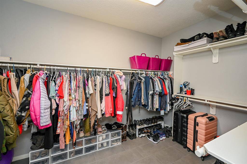 Spacious walk-in closet with ample hanging space, shelving, and room for shoes and luggage. Bright, organized, and functional.