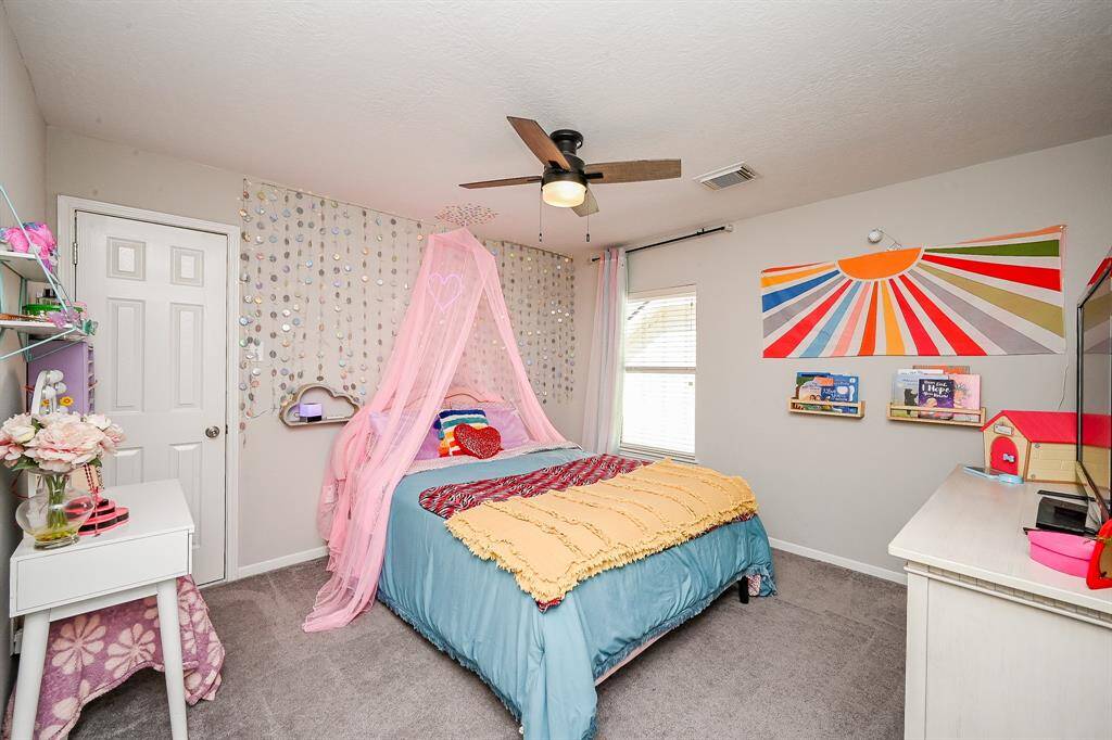 This cozy bedroom features a ceiling fan, and ample natural light from the window.