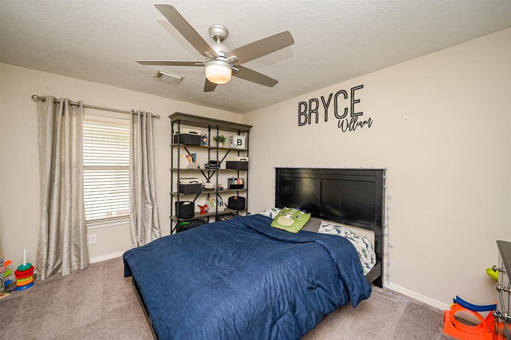 This is a cozy bedroom featuring a ceiling fan, neutral walls, and carpeted flooring.