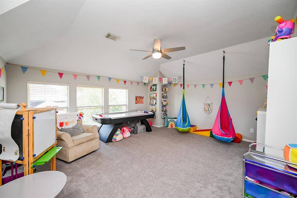 Spacious playroom with carpeted floors, and plenty of natural light from three windows. Perfect for children's activities and relaxation.