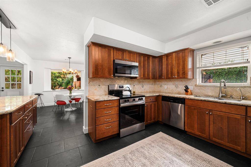 Kitchen with tile flooring and stained cabinets, features stainless appliances: new microwave, new range, new dishwasher.