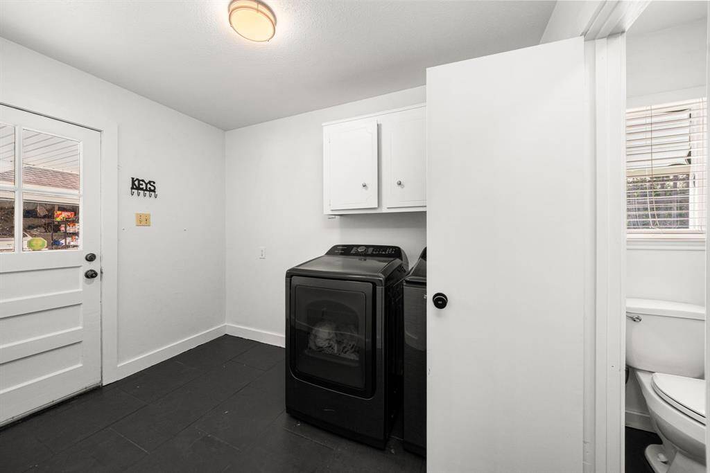 Utility room and powder bath have black tile floors and leads to garage