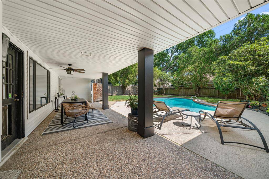 Covered patio overlooks large yard and sparkling pool