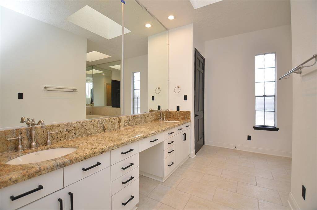 The primary bathroom has a granite vanity with double sinks, large mirrors, and a makeup counter.