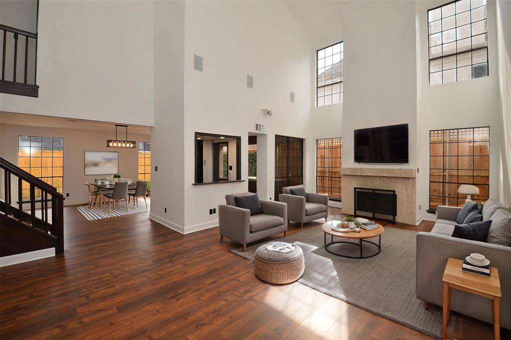The living room is large, with high ceilings and a fireplace. Virtually staged photo.