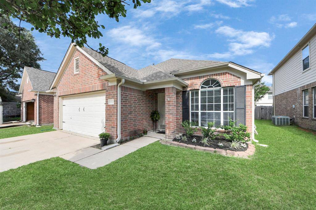 This house features a classic red brick exterior, a two-car garage, and inviting curb appeal.