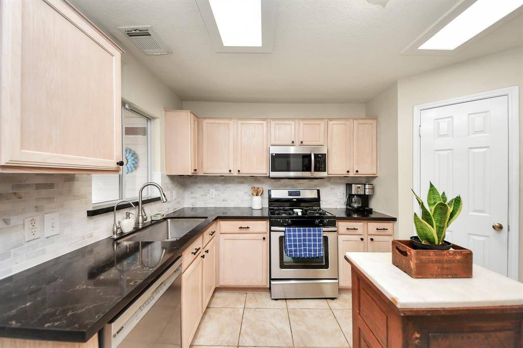 The kitchen is a standout feature, boasting sleek quartz countertops, a stylish tile backsplash, and stainless steel appliances that elevate the space. Please note: the kitchen island is not included with the home.