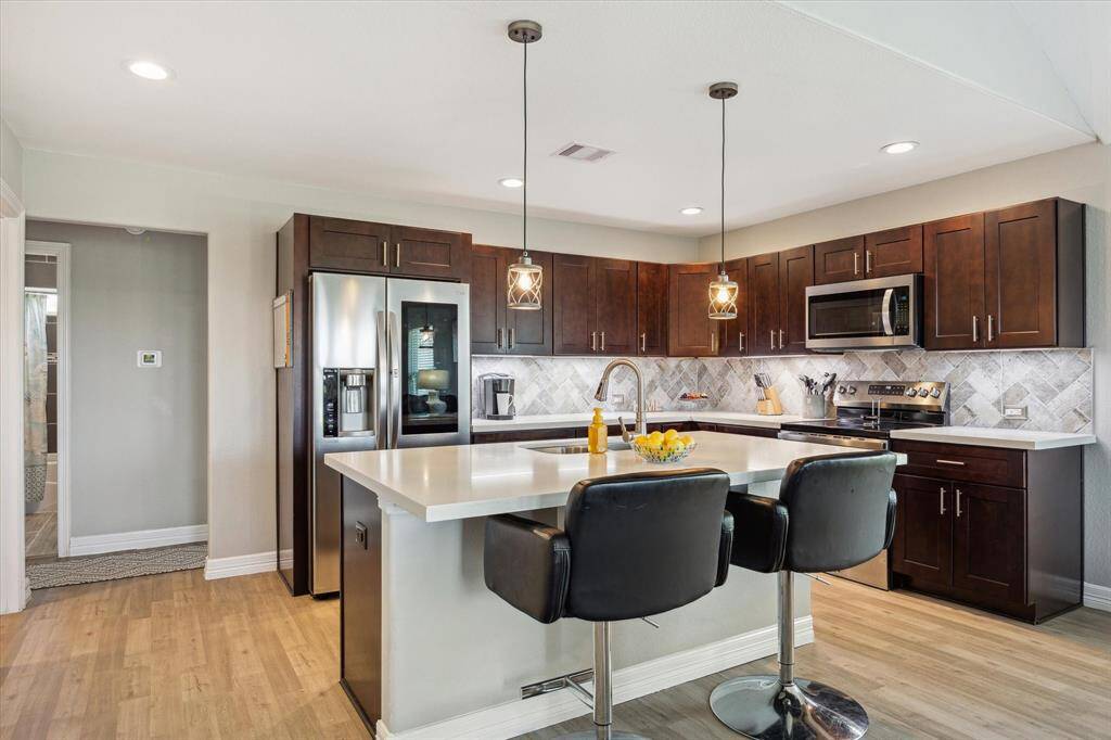 The countertops are a pretty Quartz pattern and there's under-cabinet lighting, as well as soft touch/self close cabinets and drawers. The hall bath is through the opening, and the other two bedrooms are on either side.