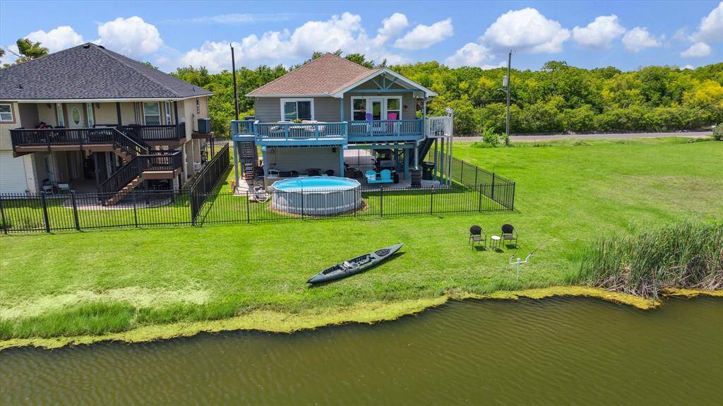 Here's the view of the back of your property. You can fish in the stocked pond or kayak. The bird-watching down here is amazing. There's an above-ground pool that could be removed if you're not a fan, but the sellers love taking a dip and enjoying being outside. It's the perfect outdoor setup for those who want to have fun in the sun by the water.