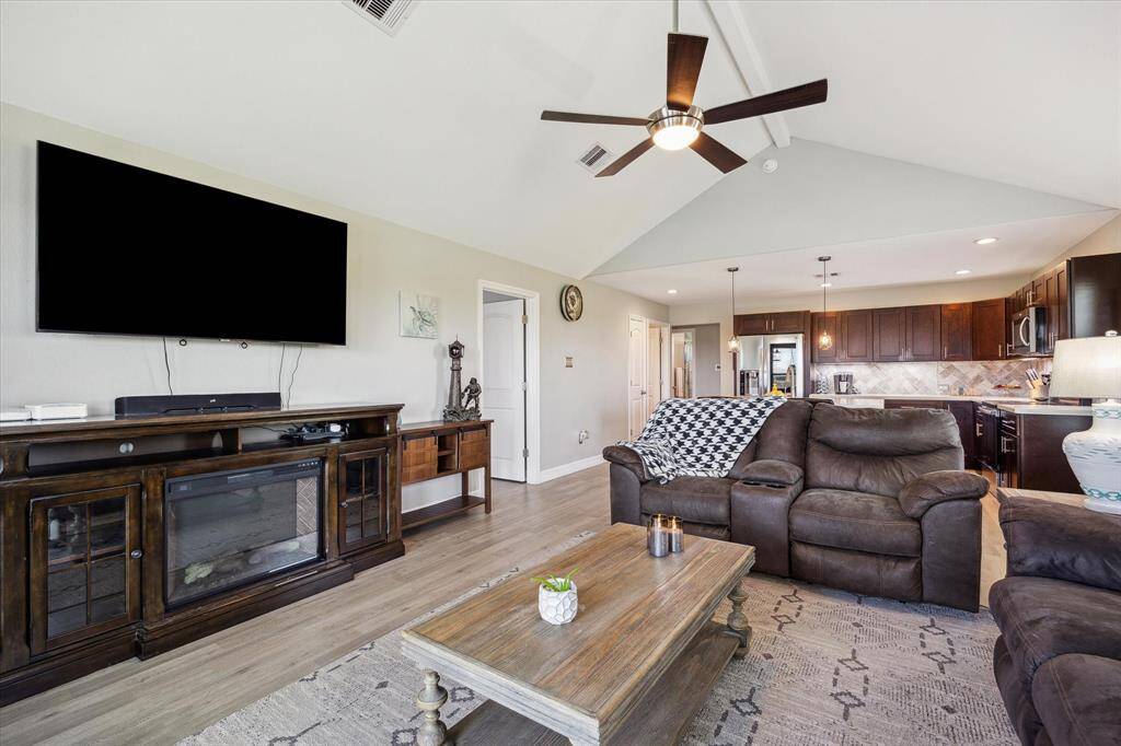 This is our view as we enter. It's a big, open living room with vaulted ceilings, a nice fan, luxury vinyl plank floors, and it opens to the kitchen.