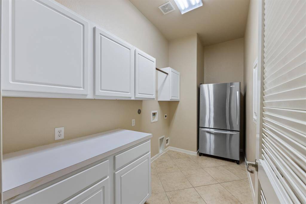 To the right of the foyer, next to the dining room, is the laundry room featuring tile floors, built-in cabinets, and counters.