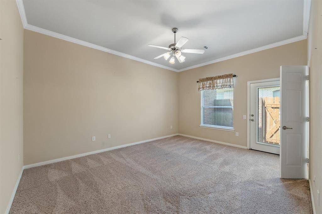 The spacious secondary bedroom boasts carpeted floors, crown molding, and ceiling fans for comfort and style. It offers a bright, inviting space ideal for family or guests. There is also a charming exterior door to a small patio next to a gate to backyard.