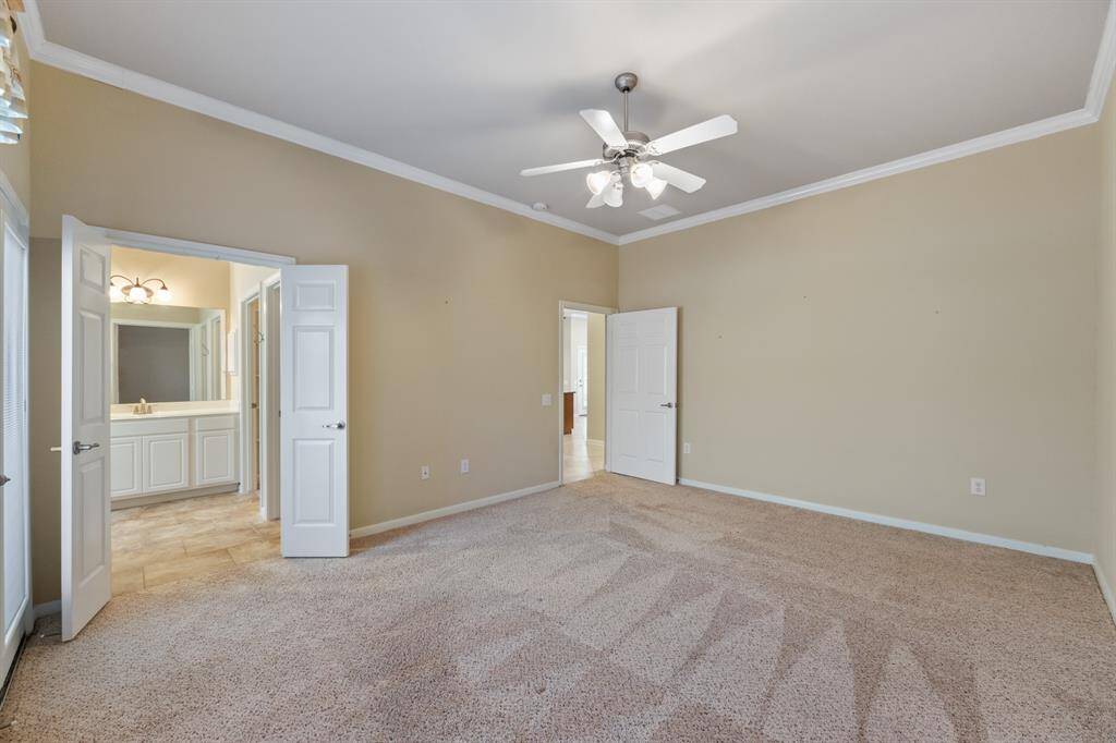 The primary bedroom features plush carpet and elegant crown molding, creating a cozy and refined retreat. This spacious room offers a peaceful sanctuary with classic touches.