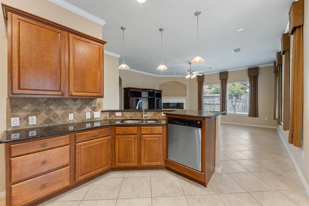 To the right of the entryway is the kitchen, featuring tile floors, crown molding, and sleek granite countertops.