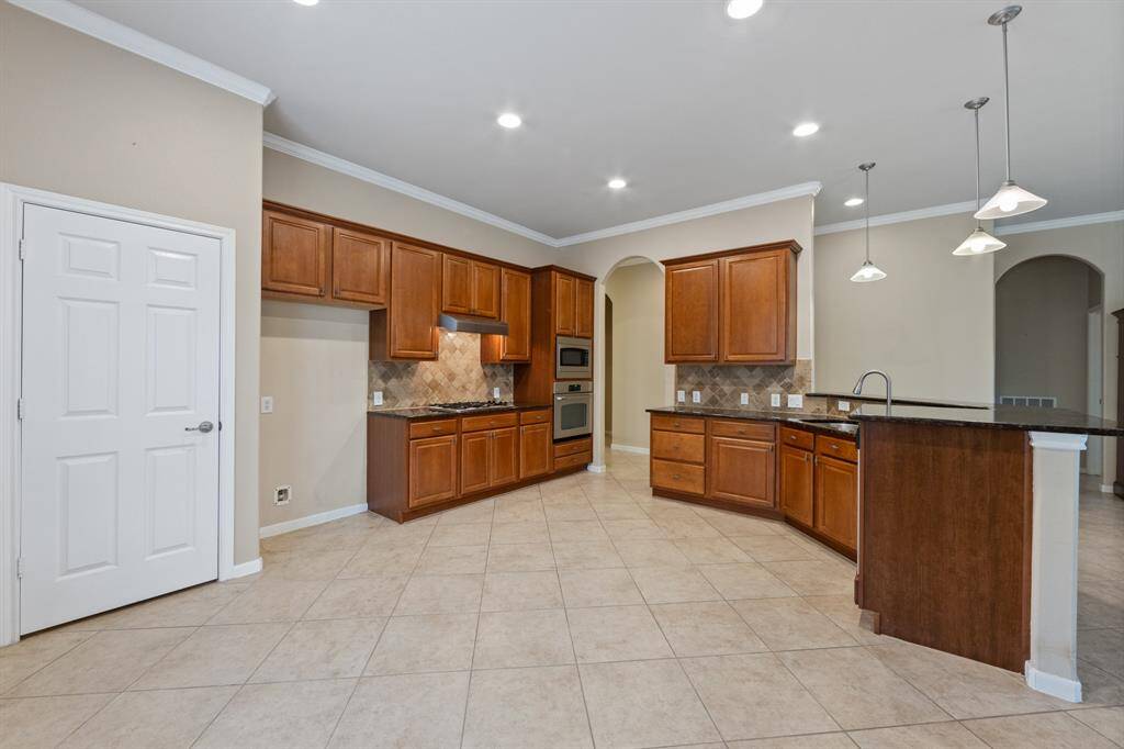 The kitchen offers plenty of storage with warm, wood-look cabinetry and stylish hanging light fixtures over the breakfast bar, creating a functional and inviting space for everyday living.