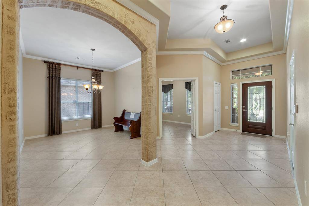 As soon as you step through the beautifully adorned glass front door, you're welcomed by a spacious entryway featuring elegant crown molding throughout, making it refined and inviting interior.
