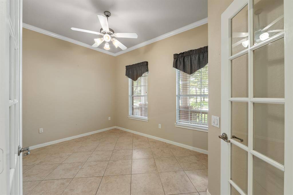 To the right of the entry is a private study featuring crown molding and elegant French doors. This versatile space is perfect for a home office or quiet reading area also featuring a convenient ceiling fan.