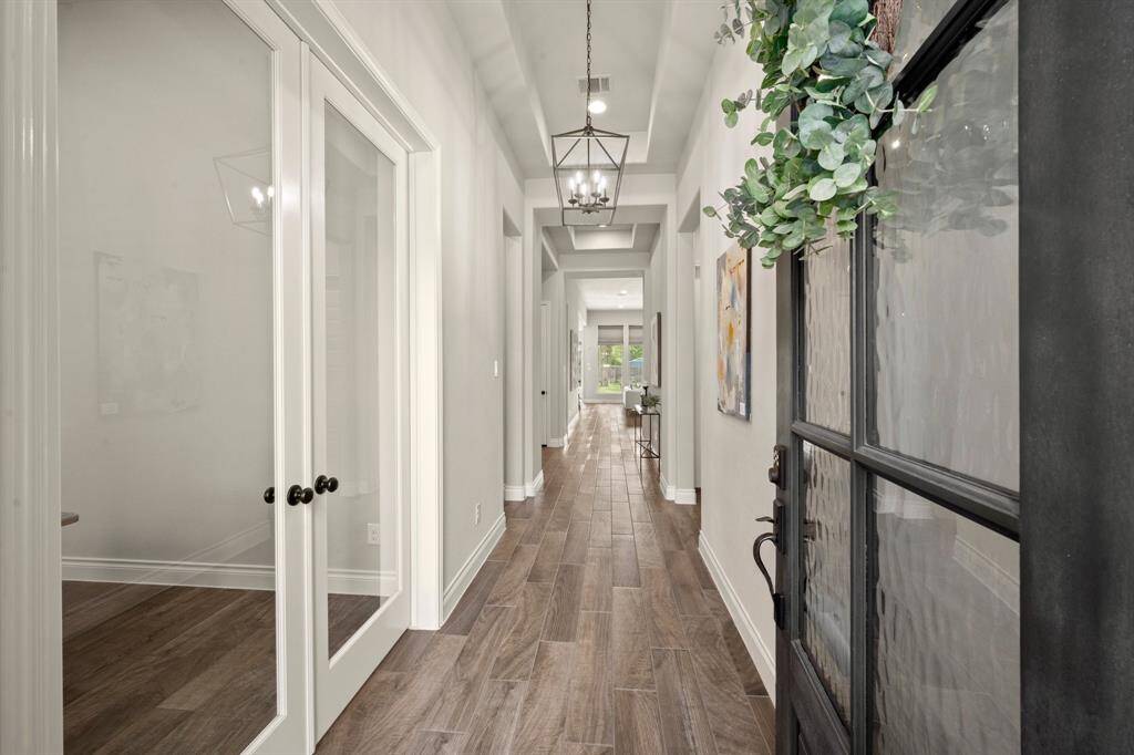 Welcome to your bright entryway from the garage, featuring elegant wood floors, chic lighting, and convenient built-in storage with seating.
