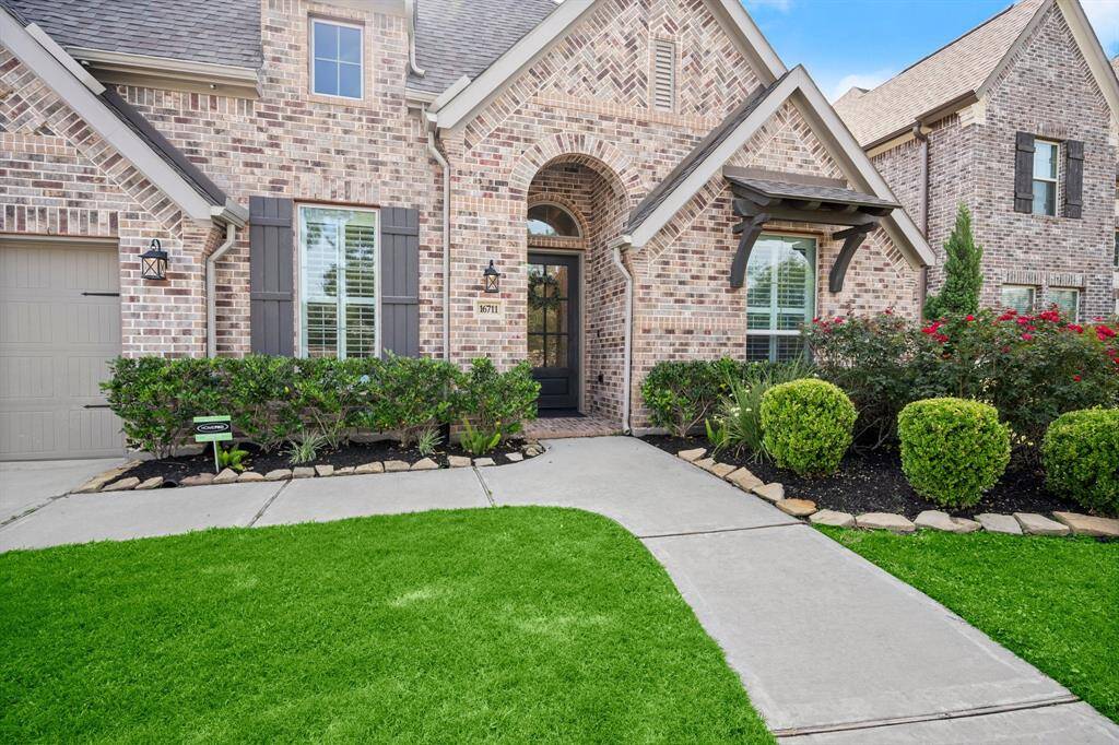 Experience timeless elegance in this charming brick home featuring a welcoming arched entrance, classic shutters, and a gable roof. The pristine front yard and manicured bushes boost its irresistible curb appeal.
