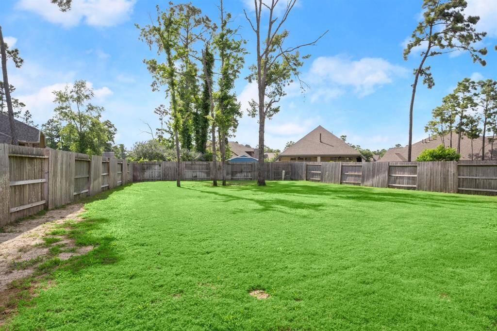 Expansive fenced backyard with lush grass and mature trees—perfect for a pool, outdoor fun, and privacy.