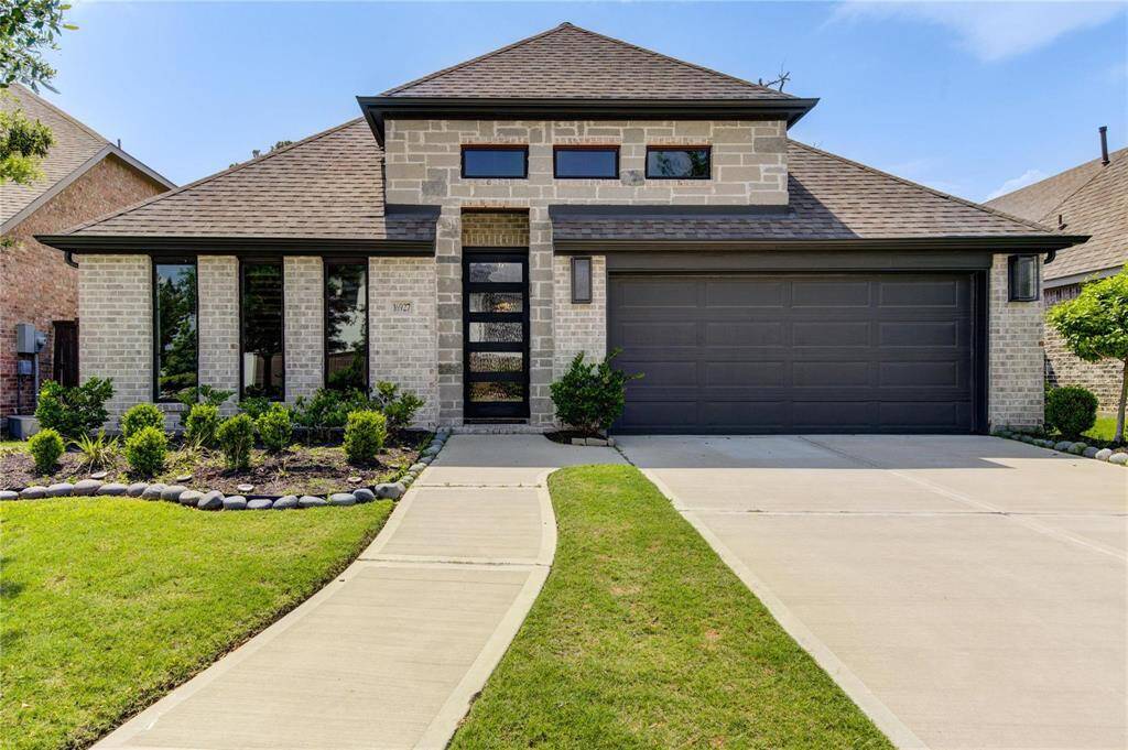 This modern 1-story Perry home features a sleek brick & stone exterior with large, decorative windows. The simple but elegant landscaping adds to its curb appeal.