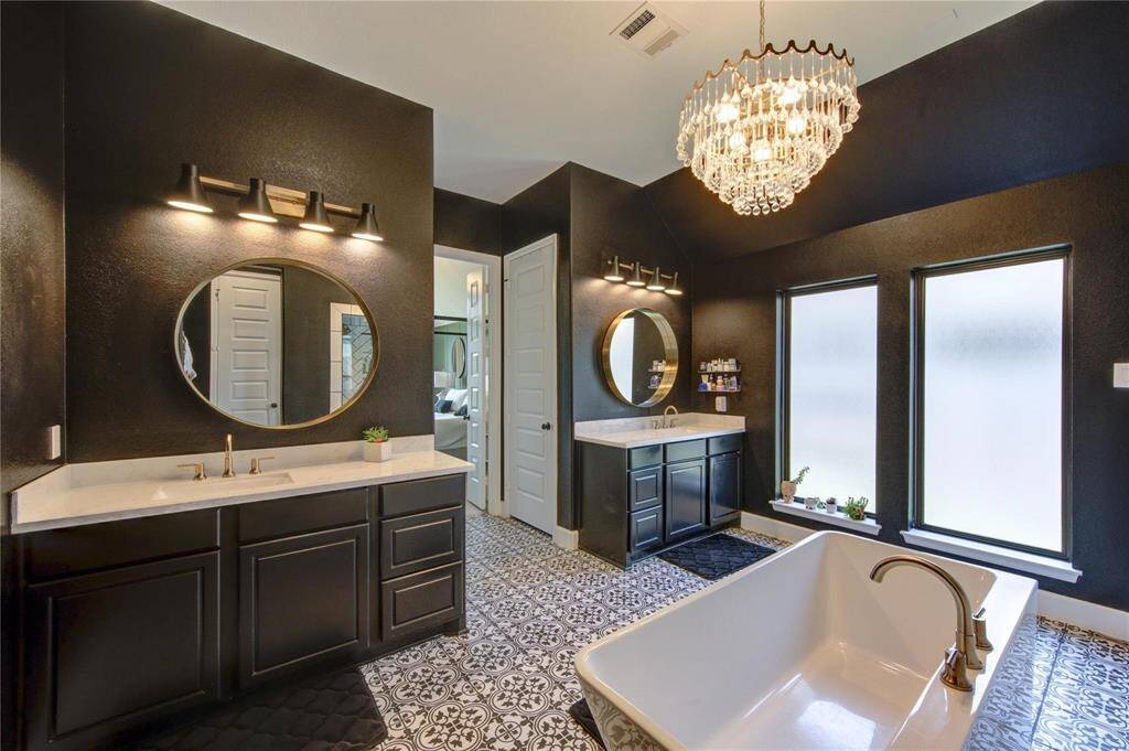 The luxurious primary bathroom features elegant quartz countertops, custom mirrors and lighting, and dual sinks.