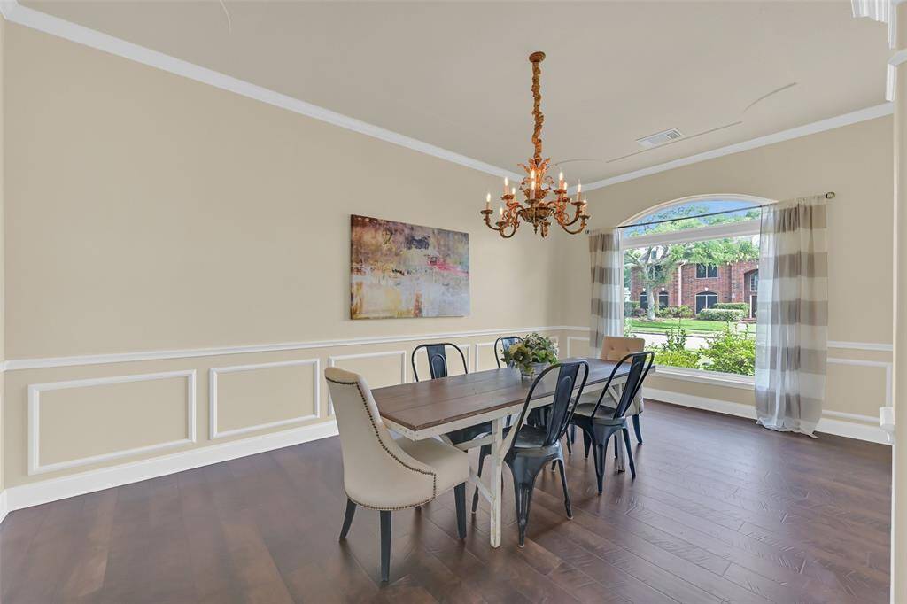 Elegant formal dining room with Pergo 24+ wood flooring, classic wainscoting, and a vintage gold chandelier that adds timeless charm. Oversized energy-efficient window fills the space with natural light and a picturesque front view.